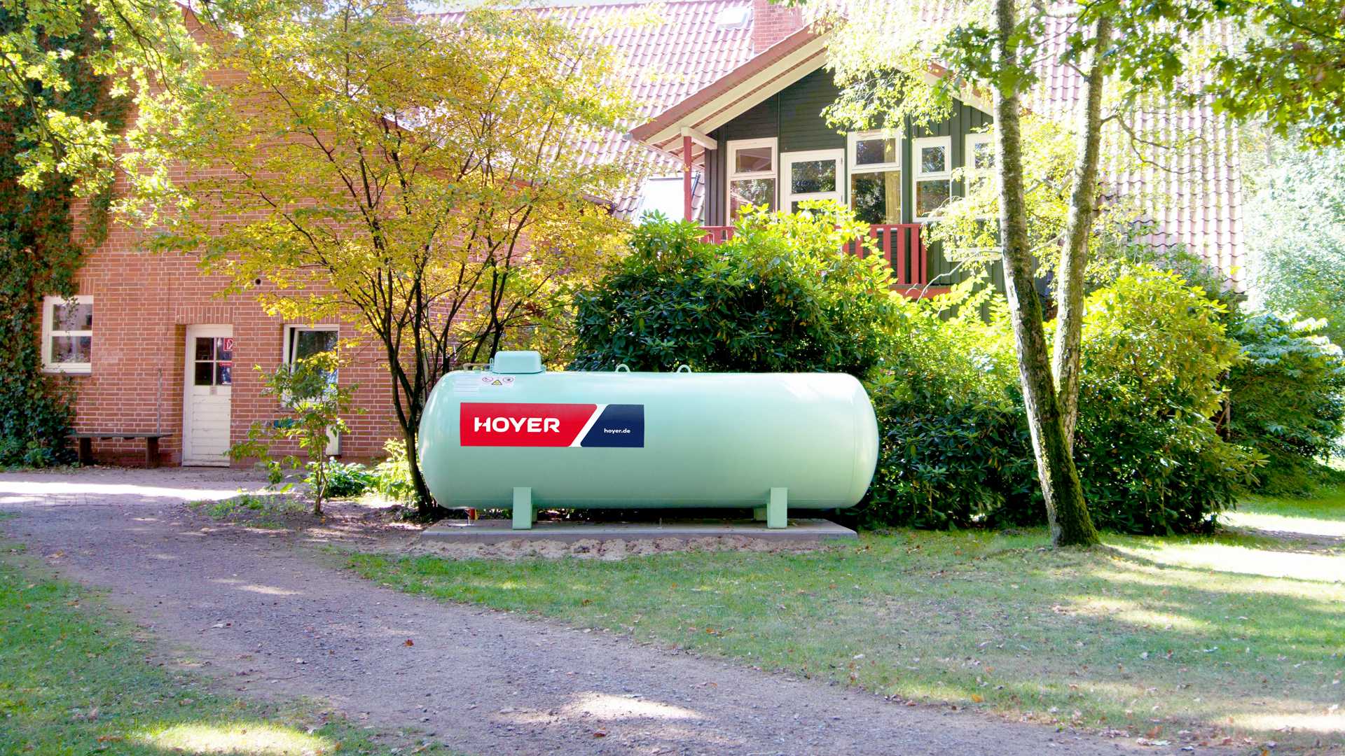 Hoyer Fluessiggastank vor einem Haus und gruenen Baeumen