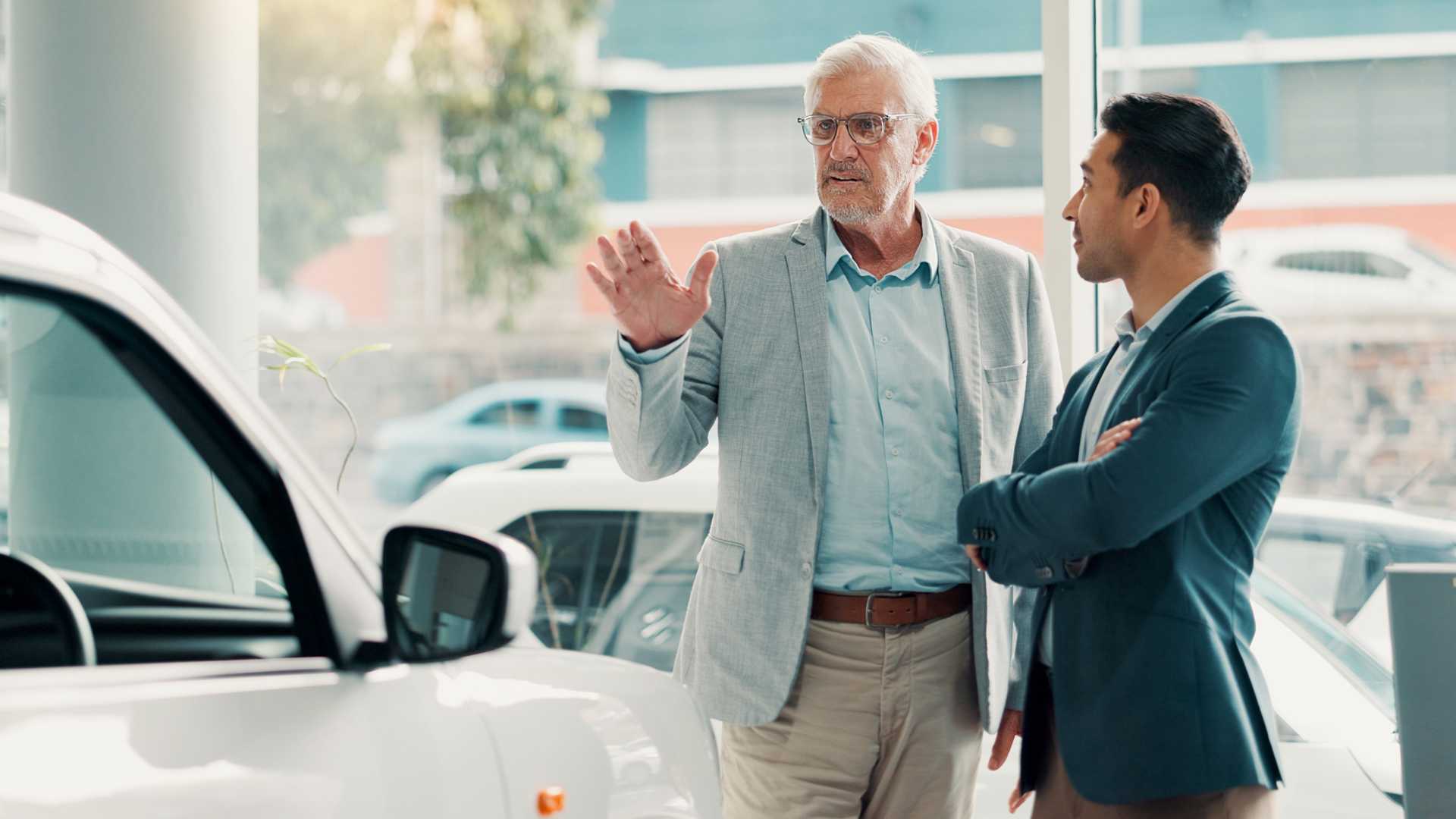 Zwei Menschen stehen vor einem Auto in einem Autohaus